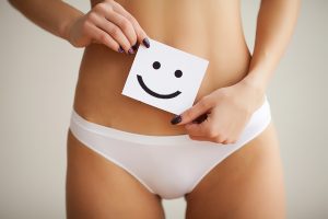 Woman holding paper with sad smile mark over her stomach. Health hygiene sexual education concept